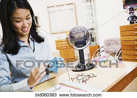 Asian optometrist cleaning eyeglasses View Large Photo Image Stock Image - Asian optometrist cleaning eyeglasses. Fotosearch