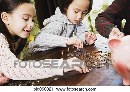 Stock Image - Asian siblings counting coins. Fotosearch