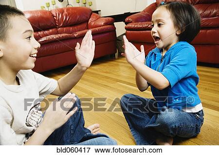 Stock Photo - Asian siblings playing clapping game. Fotosearch