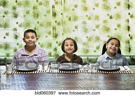 Asian siblings sitting at dinner table View Large Photo Image Stock Photo - Asian siblings sitting at dinner table. Fotosearch