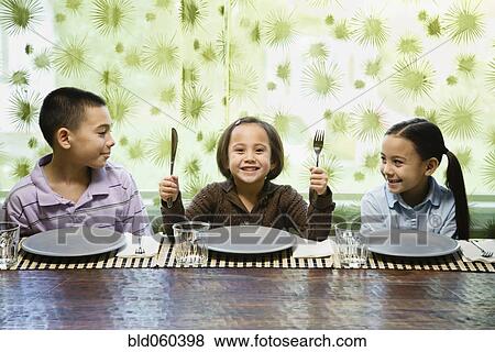 Asian siblings sitting at dinner table View Large Photo Image Stock Photo - Asian siblings sitting at dinner table. Fotosearch