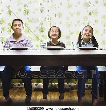 Stock Photo - Asian siblings sitting at dinner table. Fotosearch