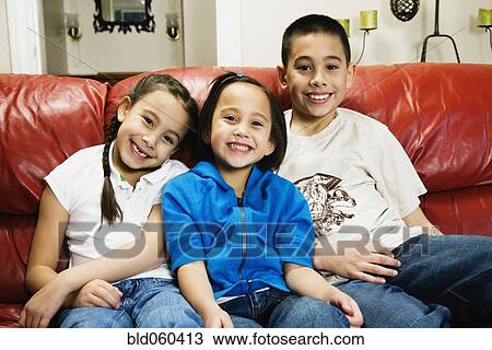 Asian siblings sitting on sofa View Large Photo Image Stock Image - Asian siblings sitting on sofa. Fotosearch
