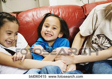 Stock Photography - Asian siblings tickling sister. Fotosearch