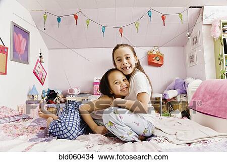 Asian sisters hugging on bed View Large Photo Image Picture - Asian sisters hugging on bed. Fotosearch