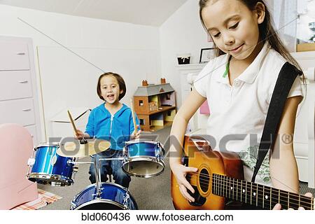 Stock Photograph - Asian sisters playing drums and guitar. Fotosearch