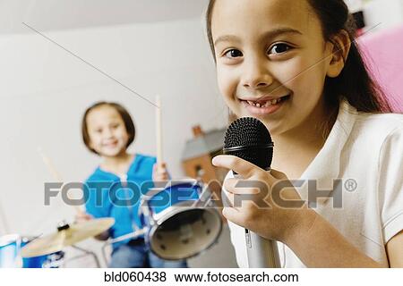 Stock Photo - Asian sisters playing drums and singing. Fotosearch