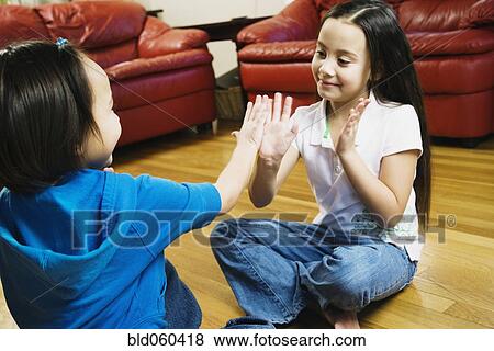 Stock Photo - Asian sisters playing paddy cake. Fotosearch