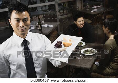 Stock Photo - Asian waiter carrying plate of food. Fotosearch