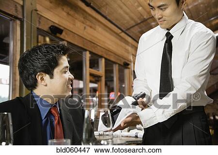 Asian waiter showing wine to customer View Large Photo Image Stock Photo - Asian waiter showing wine to customer. Fotosearch