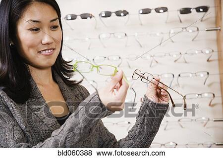 Asian woman comparing eyeglasses View Large Photo Image Stock Photo - Asian woman comparing eyeglasses. Fotosearch