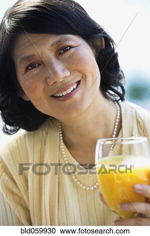 Asian woman drinking orange juice View Large Photo Image Stock Image - Asian woman drinking orange juice. Fotosearch