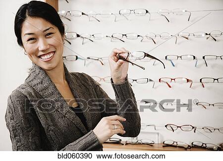 Stock Image - Asian woman holding eyeglasses. Fotosearch
