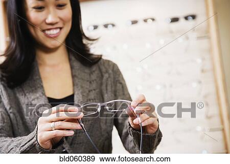 Asian woman looking at eyeglasses View Large Photo Image Stock Photo - Asian woman looking at eyeglasses. Fotosearch