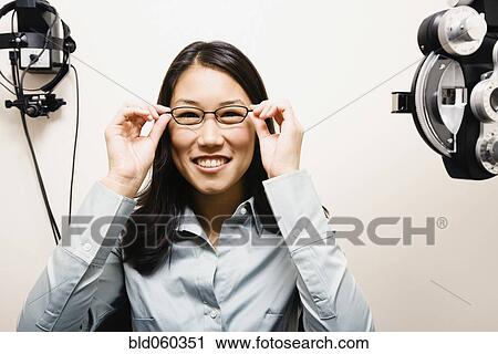 Asian woman putting on eyeglasses View Large Photo Image Stock Image - Asian woman putting on eyeglasses. Fotosearch