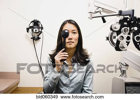Stock Photo - Asian woman taking eye exam. Fotosearch