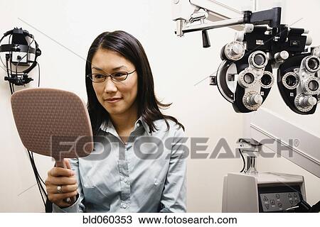 Stock Image - Asian woman trying on eyeglasses. Fotosearch
