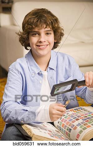 Stock Image - Hispanic boy holding stamp and magnifying glass. Fotosearch
