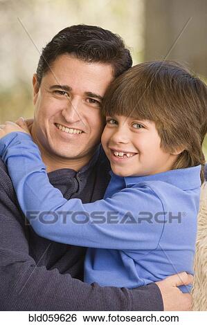 Stock Photograph - Hispanic father and son hugging. Fotosearch