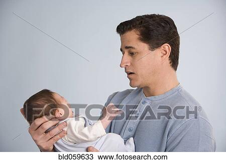 Stock Image - Hispanic father holding baby. Fotosearch