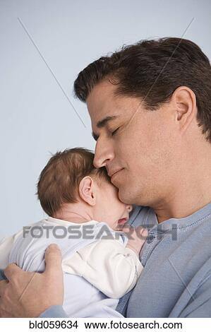 Picture - Hispanic father hugging baby. Fotosearch