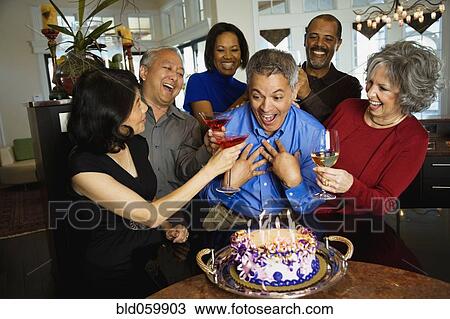 Stock Image - Hispanic man celebrating birthday with multi-ethnic friends. Fotosearch