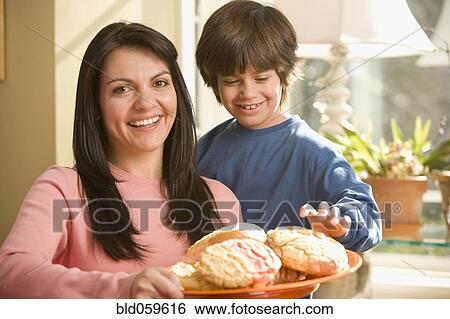 Stock Photograph - Hispanic mother and son holding plate of cookies. Fotosearch