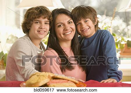 Stock Photo - Hispanic mother and sons next to plate of cookies. Fotosearch