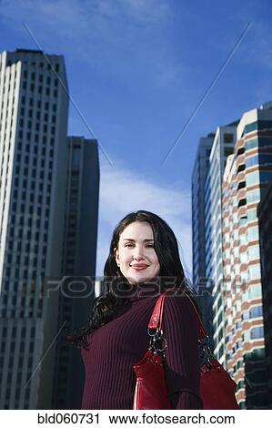 Hispanic woman in front of high-rises View Large Photo Image Stock Image - Hispanic woman in front of high-rises. Fotosearch