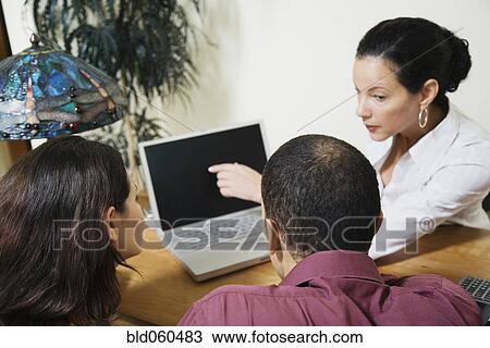 Mixed Race businesswoman and clients looking at laptop View Large Photo Image Stock Image - Mixed Race businesswoman and clients looking at laptop. Fotosearch