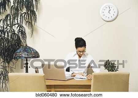 Stock Image - Mixed Race businesswoman looking at paperwork. Fotosearch