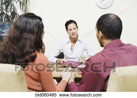Stock Photography - Mixed Race businesswoman talking to clients. Fotosearch