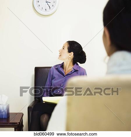 Stock Photo - Mixed Race female psychiatrist looking at clock. Fotosearch