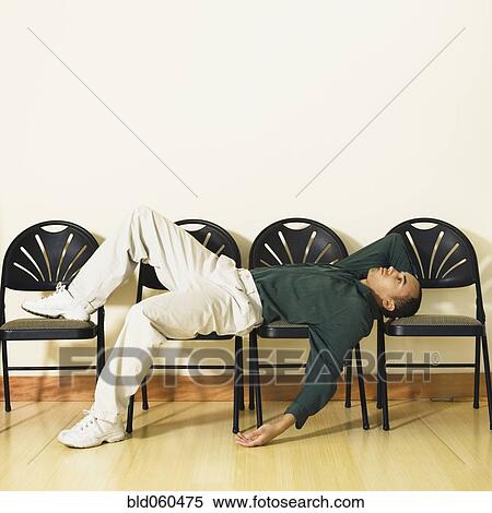 Stock Photography - Mixed Race man laying in waiting area. Fotosearch