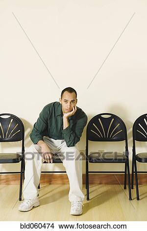 Picture - Mixed Race man sitting in waiting area. Fotosearch