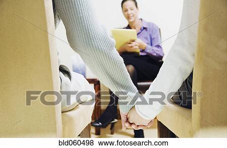 Stock Photo - Multi-ethnic couple holding hands at therapy session. Fotosearch
