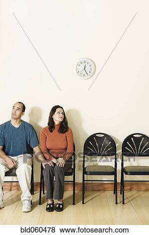 Stock Photo - Multi-ethnic couple sitting in waiting area. Fotosearch