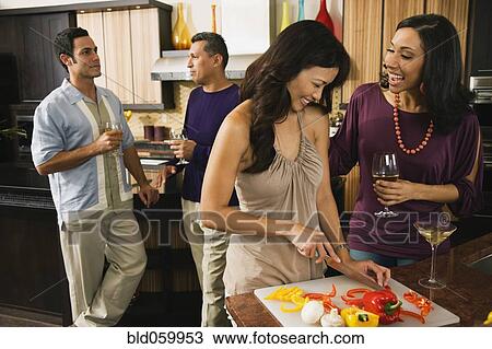 Stock Image - Multi-ethnic friends drinking and preparing food. Fotosearch