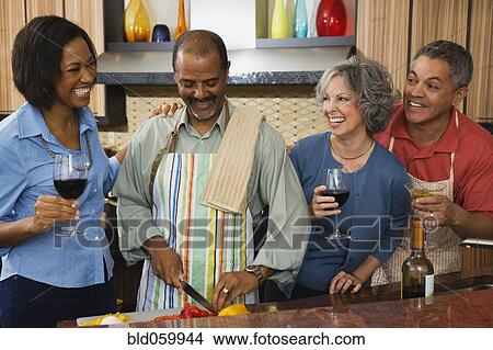 Picture - Multi-ethnic friends drinking wine and preparing food. Fotosearch