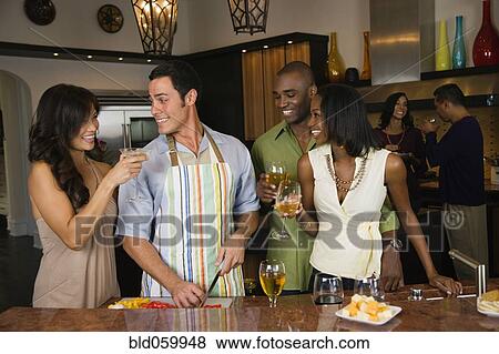 Stock Photo - Multi-ethnic friends drinking wine and preparing food. Fotosearch