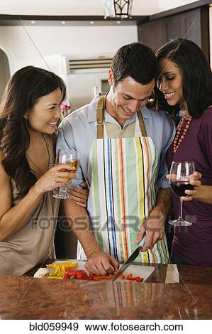 Stock Photo - Multi-ethnic friends drinking wine and preparing food. Fotosearch