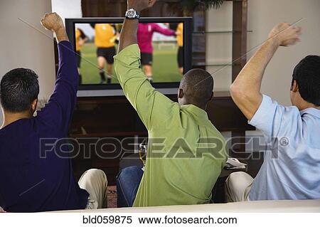 Multi-ethnic men cheering on sofa View Large Photo Image Stock Photography - Multi-ethnic men cheering on sofa. Fotosearch