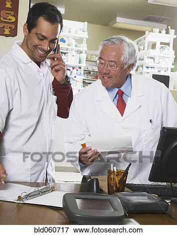 Stock Photo - Multi-ethnic pharmacists looking at paperwork. Fotosearch