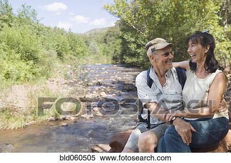 Multi-ethnic senior couple hugging next to stream View Large Photo Image Stock Photography - Multi-ethnic senior couple hugging next to stream. Fotosearch