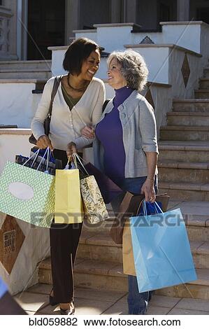 Stock Image - Multi-ethnic women carrying shopping bags. Fotosearch
