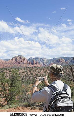 Senior man taking photograph of desert landscape View Large Photo Image Stock Photo - Senior man taking photograph of desert landscape. Fotosearch