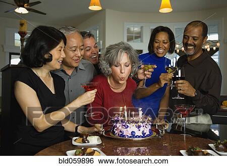 Stock Photograph - Woman celebrating birthday with multi-ethnic friends. Fotosearch