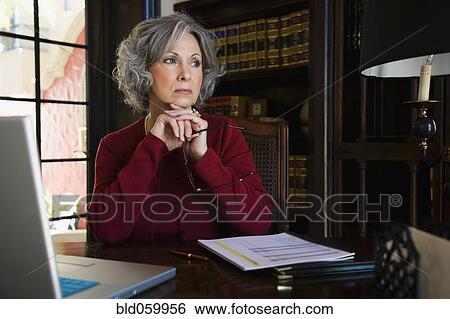 Woman sitting at desk View Large Photo Image Stock Photograph - Woman sitting at desk. Fotosearch
