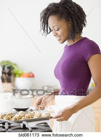 Stock Image - Africa woman baking cookies. Fotosearch