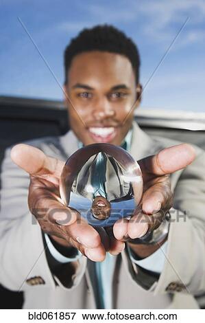 Stock Photo - African businessman holding crystal ball. Fotosearch